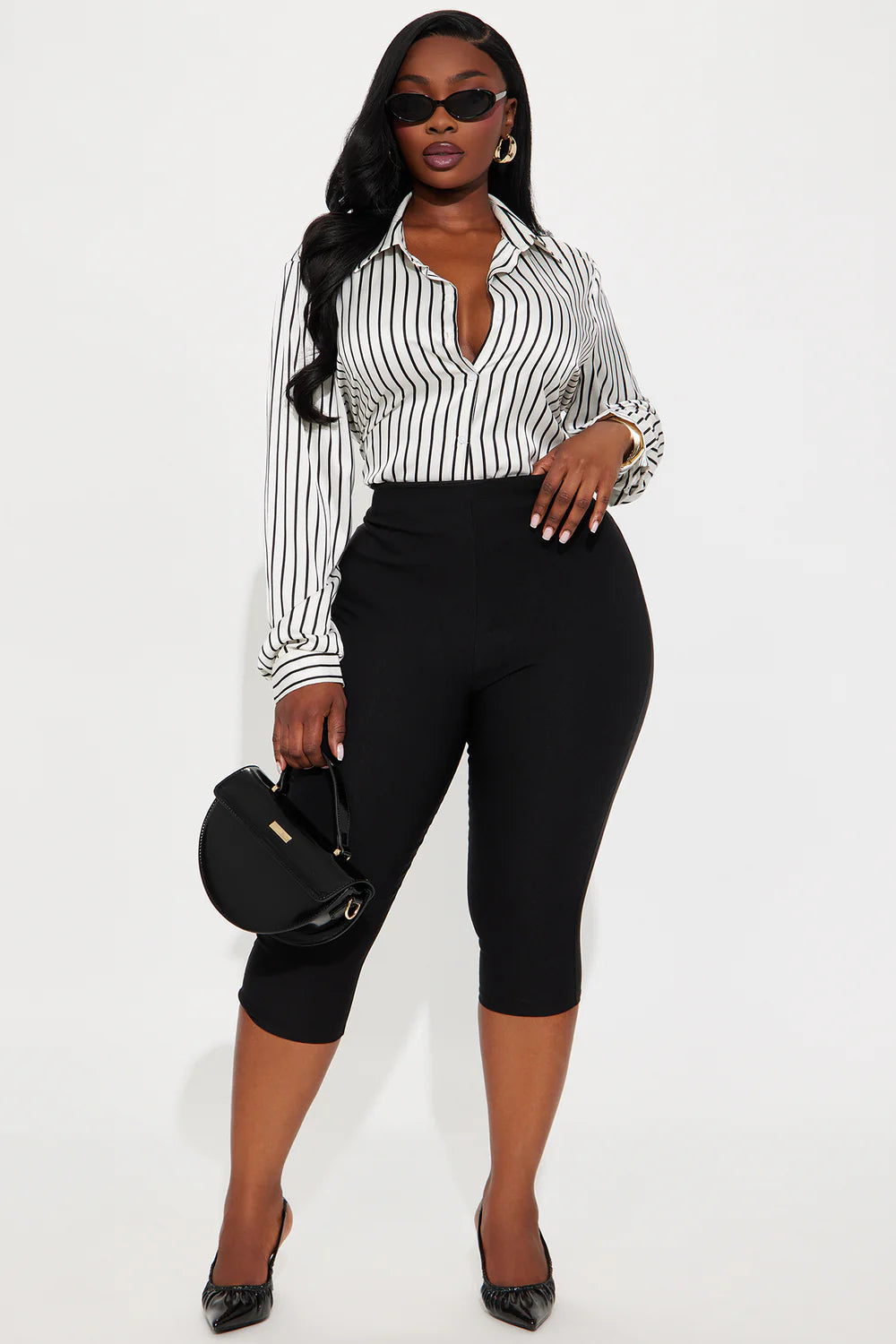 Woman wearing a black and white striped shirt with black capri pants on a white background
