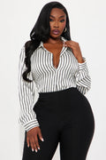 Woman wearing a black and white striped blouse with high-waisted black pants on a white background