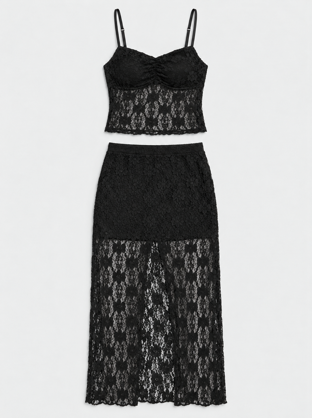 Flat lay of a black lace camisole and matching long skirt on a light grey background